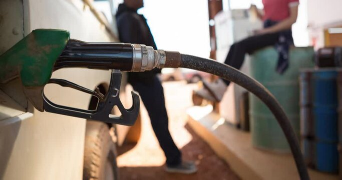 Diverse man and woman filling up truck using fuel pump at petrol station