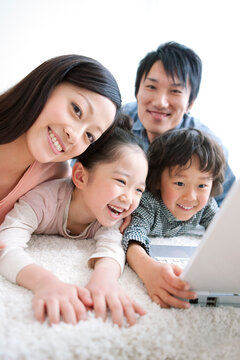 ノートパソコンと笑顔の家族4人