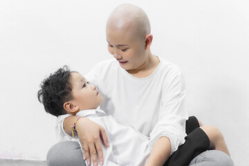 Young adult female cancer patient spending time with son at home, relaxing on the couch. Cancer and family support concept.