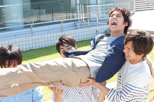 胴上げをする大学生4人