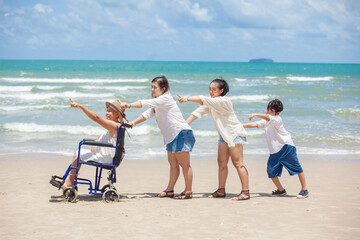 Disabled woman asia in a wheelchair with his family on the beach. Wheelchair woman sitting relax on the beach.  family relax concept