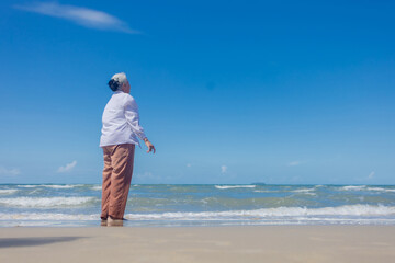 Portrait of healthy senior woman  standing on the beach. Happy summer holiday on the beach