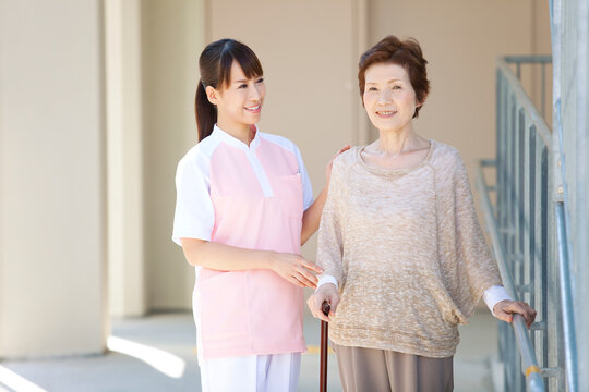 女性介護士と杖をつく中高年女性