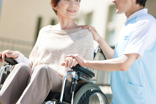 車いすに乗った中高年女性に寄り添う介護士