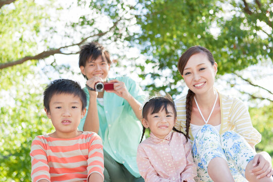 ビデオ撮影する父親と笑顔の家族3人