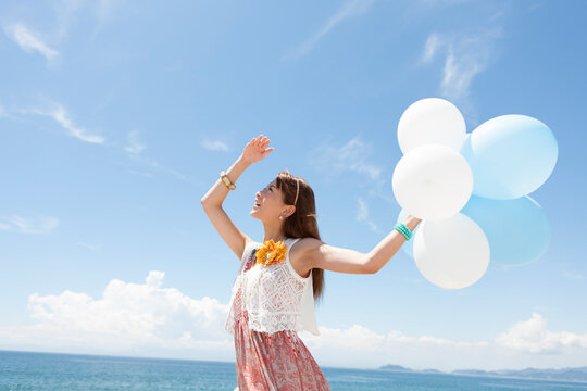 海岸で風船を持っている笑顔の女性
