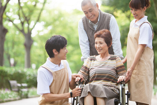 車いすに座るシニア女性とシニア男性と介護士