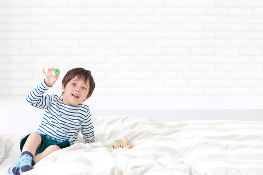 ベッドの上で積み木で遊ぶ男の子