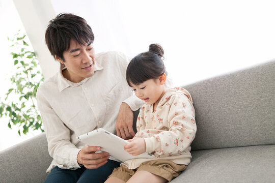 タブレットPCを見る女の子と父親