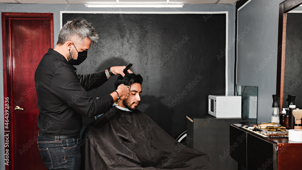 Wall mural young man getting a haircut in a barber shop