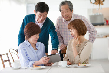 タブレットPCを見て話す中高年4人