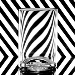 refraction of light by a glass on a black and white striped background. Abstract glass art.