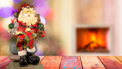 Santa Claus doll on the table and colorful blurred background with lights and fireplace. Selective focus.