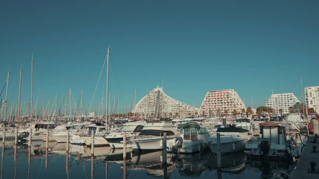 Parked Grande Mottes Yacht rocking on water and buildings at sunny day.