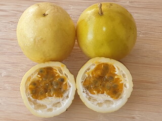 Two whole passion fruits and one cut in half with its seeds.