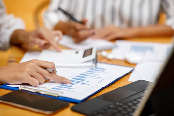 Fototapeta premium Close up of businesswoman working on desk office with using a calculator to calculate the numbers, finance accounting concept. 