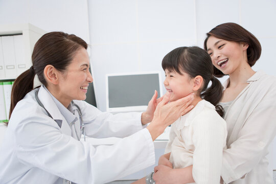 笑顔を浮かべる母娘と女医
