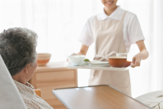 食事を持ってくる女性とシニア女性