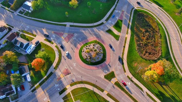 Time lapse traffic flows through beautiful modern roundabout in Autumn morning sunshine, aerial time lapse, seamless loop.