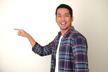 Side view of adult Asian man pointing and showing happy face expression