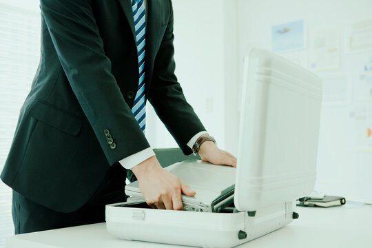 アタッシュケースに荷物を入れるビジネスマン