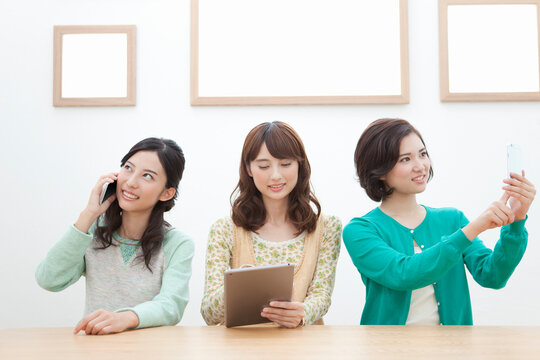 スマートフォン等を持つ女性3人