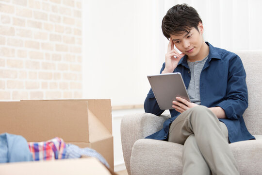 段ボールとタブレットPCを見る男性
