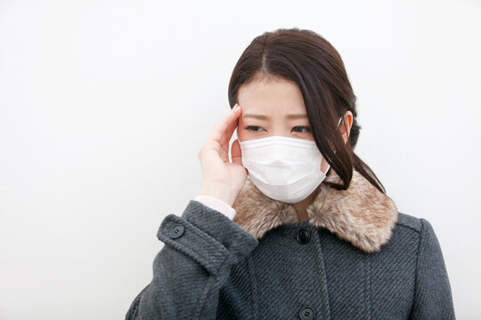 こめかみを押さえる女性