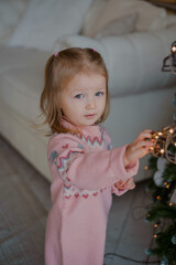 Portrait of a charming little girl decorating a Christmas tree.  Christmas 2022.