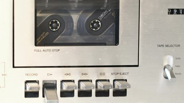 man turns on a tape recorder with cassette close-up