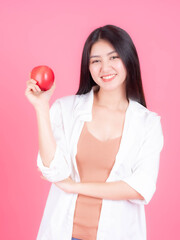 Obraz na płótnie Canvas beautiful Asian woman cute girl feel happy eating red apple fruit for good health isolated on pink background with copy space - lifestyle healthy woman concept