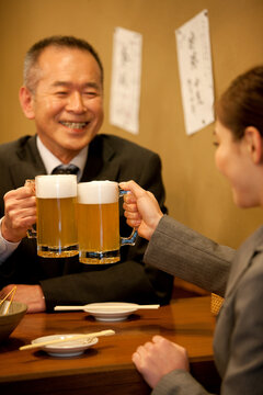 ビールで乾杯するビジネスマンとビジネスウーマン