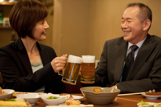 ビールで乾杯するビジネスマンとビジネスウーマン