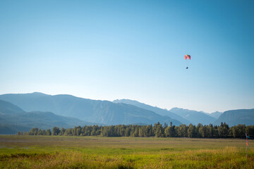 Paragliding tandem makes a descent in Revelstoke. Mountains, marsh, British Columbia