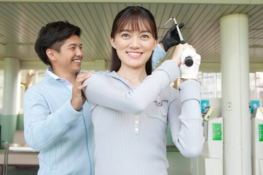 女性にゴルフを教える男性