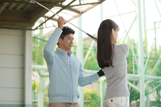女性にゴルフを教える男性