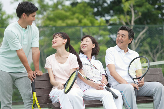 テニスコートで休憩する男女4人