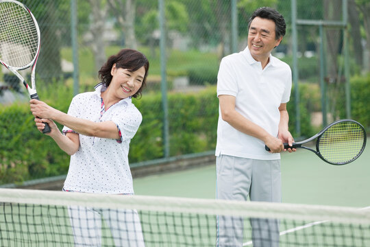 テニスをする中高年カップル