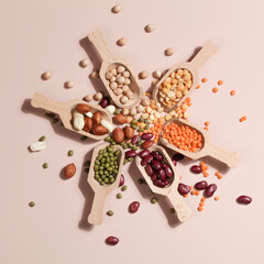 Vegan protein source. Beans, peas, chickpeas, lentils, mung bean, peanut in wooden spoon on beige background.