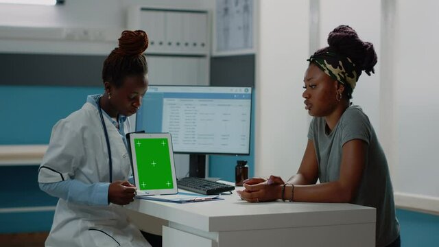 African american doctor and patient looking at green screen on tablet for checkup visit. Black medic vertically holding isolated background and mockup template with chroma key on display