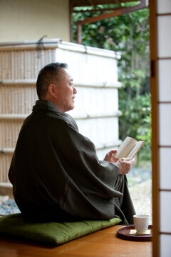 縁側に座って本を読む中高年男性