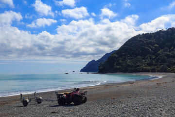 A quad bike and trailer on a pebble beach at Hawai, a remote beach in the Bay of Plenty, New Zealand © Michael