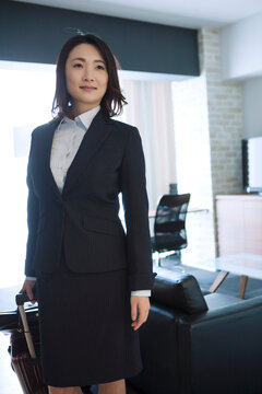 ホテルの部屋でスーツケースを引くビジネスウーマン