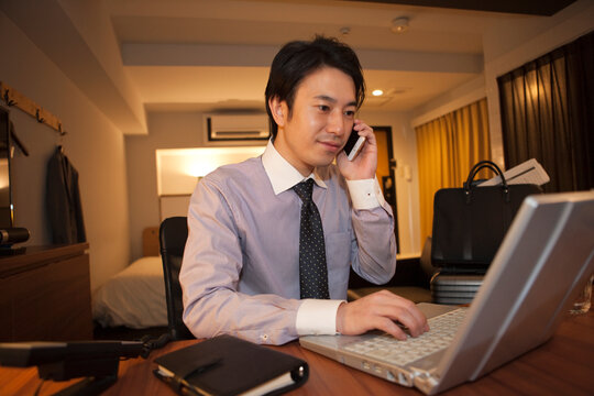 ホテルの部屋でパソコンを操作する男性