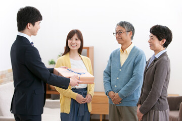 贈答品を差し出す男性と家族