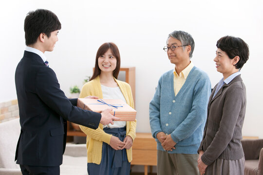 贈答品を差し出す男性と家族