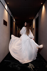 A young beautiful bride runs down the corridor of the hotel. Wedding photo shoot at the hotel.