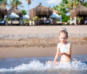 Little girl playing on the beach by the sea