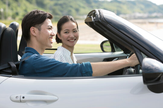 海辺をドライブするカップル