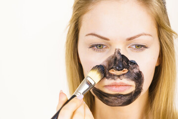 Girl being apply black mask to skin face